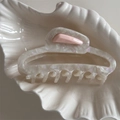Dettaglio del fermaglio per capelli in acetato con trama iridescente in una ciotola di ceramica - Bianco Madreperla