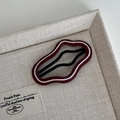 Close-up of a red wavy hair clip with white scalloped lace edges on a beige tray - Cloud White Border Style