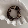 Dettaglio dell'elastico leopardato con perla in resina su un vassoio a conchiglia - Stampa Leopardata Scura Base