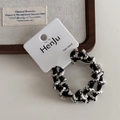 Detail shot of black and white woven elastic hair bands on a rustic wooden tray - Black