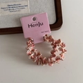 Close-up of pink and white spiral braided hair tie on display card with cozy wooden decor - Pink