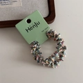 Detailed view of colorful woven elastic hair bands on a white display board - Green