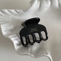 Détail d'une pince à cheveux noire brillante montrant le logo doré France Handmade - Noir