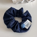 Détail d'un chouchou en denim bleu marine avec perle bleue et étiquette blanche sur plateau - Chouchou en Denim Bleu Foncé (Groupe Marine-Perle Bleue)