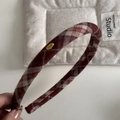 Close-up of red and grey plaid fabric headband featuring a small gold logo tag - Red Checkered Velvet Surface - Headband