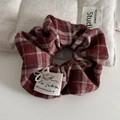 Detail of red plaid scrunchie with faux pearl flower and a handmade fabric label - Red Checkered Velvet Surface - Scrunchie