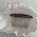 Nahaufnahme eines 10-Zahn Haarkamms mit Leopardenmuster auf weißem Porzellanteller - Beige Leopard
