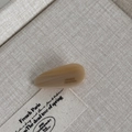 Detail of cream acetate teardrop hair clip with France Handmade engraving on linen - Apricot