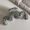 Dettaglio macro della molletta per capelli a onda con paillettes colorate e trama grigia - Bianco Tweed Paillettes-Forma M