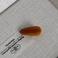 Close-up of amber teardrop acetate hair clip with handmade gold lettering on fabric - Caramel