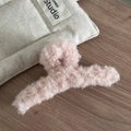 Gros plan sur une pince à cheveux en peluche rose douce sur un fond en bois sombre - Laine d Agneau Douce / Rose