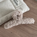 Gros plan d'une pince à cheveux en peluche douce type agneau sur un fond en bois - Laine d Agneau Douce / Chameau