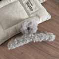 Gros plan sur une pince à cheveux en peluche grise douce avec une texture bouclée - Laine d Agneau Douce / Gris clair