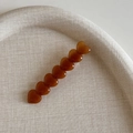 Détail de la pince à cheveux cœur ambre sur un plateau en osier au design élégant - Pince 7 Cœurs - Café