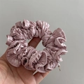 Close-up of pleated satin hair scrunchie in dusty pink with a tiny gold metal charm detail - Pink