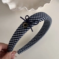 Detailansicht eines dunkelblau-weiß karierten Haarreifs mit Schleife und Goldknopf - Marineblau Gingham Stirnband