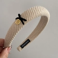 Detail of knitted headband with black velvet bow and golden metallic engraved disc - Apricot