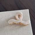 Gros plan d'une pince à cheveux en acétate blanc nacré avec design ondulé et ressort doré - Style Vague (Blanc Perle Sirène)