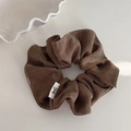 Détail macro d'un chouchou en tissu à chevrons marron foncé avec petite étiquette de nœud - Marron