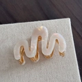 Détail d'une pince à cheveux ondulée en acétate blanc nacré avec base en métal doré - Style Courbe (Blanc Perle Sirène)