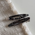 Détail de deux barrettes en acétate avec motif marbré gris sur tissu en lin - Noir et Gris