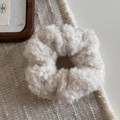 Gros plan d'un chouchou en peluche beige à texture laine d'agneau sur fond de lin - Blanc