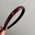 Close-up of wine red leather headband with a gold 'Love' engraved metal plate detail - Burgundy Leather-Small Gold Label