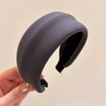 Dettaglio di un cerchietto spesso grigio scuro con trama in maglia morbida tenuto in mano - grigio scuro