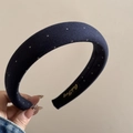 Close-up of a navy blue padded headband with small white polka dots and golden logo tag - Navy Blue