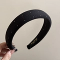Detailed close-up of a black padded headband with white polka dots and a brand label - Black