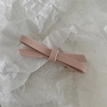 Detail of pink suede bow hair clip with golden metal fastener on textured paper - Asymmetric / Pink Cream