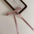 Détail d'une barrette à nœud en satin rose avec de longs rubans sur un plateau - Rose foncé