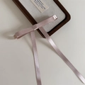 Détail du nœud papillon en satin rose pâle avec de longs rubans sur plateau - Rose Clair