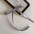 Detailed view of ballet-style gray satin bow hair clip with long ribbons on display - Gray