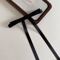 Détail d'une élégante pince à cheveux noeud noir sur un plateau à bijoux en bois de noyer - Noir