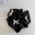 Detalle de coletero negro satinado con tres elegantes lazos de cinta en crema - Negro