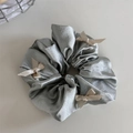 Detalle de un coletero de satén gris plateado con lazos decorativos de cinta beige - Verde
