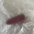 Détail d'une pince à cheveux en acétate rose poudré mat sur fond de papier froissé - Violet