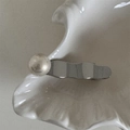 Dettaglio di un fermaglio per capelli ondulato argento con perla su vassoio ceramica - Stile Onda d'Argento