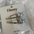 Close-up of silver alloy heart bow hair clips on a white display card minimalist style - Blue
