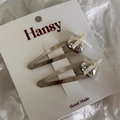 Detail view of silver heart hair clips with cream ribbon bows on brand display card - Beige