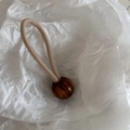 Detail of high elasticity beige hair tie with amber-textured marble bead on paper - Amber Texture Ball Style / Beige