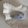 Détail d'une barrette bleu clair avec quatre petits nœuds en métal argenté sur une assiette - Pince à Cheveux Nœud en Cuir / Bleu