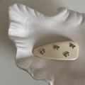 Détail d'une pince à cheveux en résine crème avec quatre nœuds en métal argenté sur plateau - Pince à Cheveux Nœud en Cuir / Poche zippée