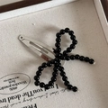 Detail view of a black beaded bow hair clip on a vintage decorative display tray - Beaded Black (Snap Clip)