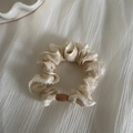 Detalle de coletero beige con bordes de encaje blanco y perla marrón sobre tela blanca - Blanco Roto