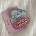 Close-up of cute cartoon puppy cloud and pink cherry hair clips on soft fabric background - Cartoon Teddy Dog