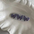 Detail view of oval acetate hair clip with elegant purple butterfly patterns on a white tray - Purple Butterfly