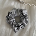 Detail of silver metallic scrunchie with delicate black ribbon bows on textured white fabric - Silver Scrunchie - Black Bow