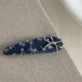 Detail of blue denim hair clip with silver metal bow and grommet accents on a beige fabric - Dark Blue Long Drop